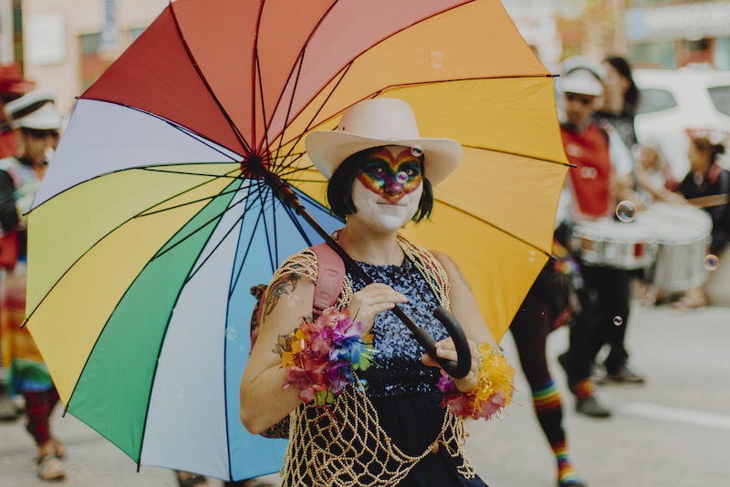 person parading in pride costume holding an umbrella