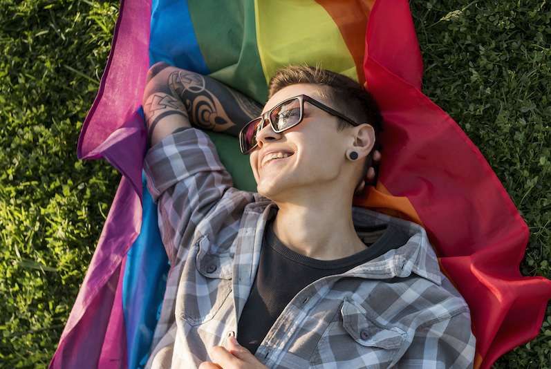 person laying on grass over pride flag