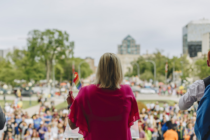 Back of woman that is giving a speech to the crowd in front of her.